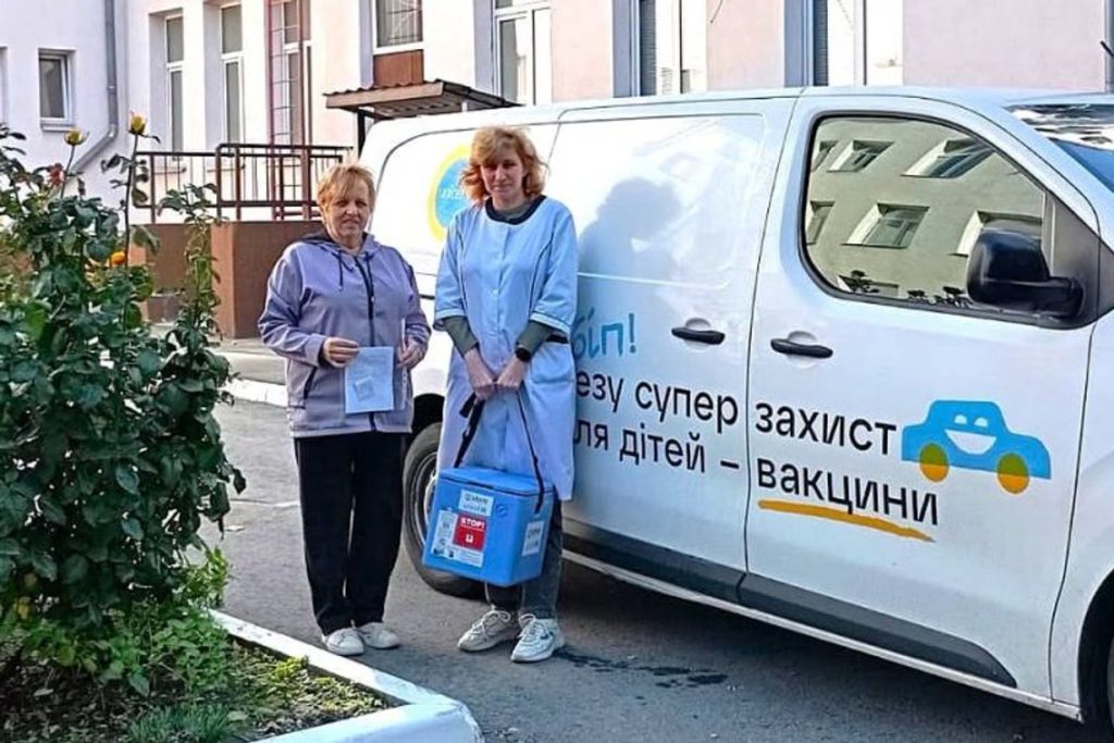 Працівниці центру контролю та профілактики хвороб із термоконтейнером для вакцин біля автомобіля